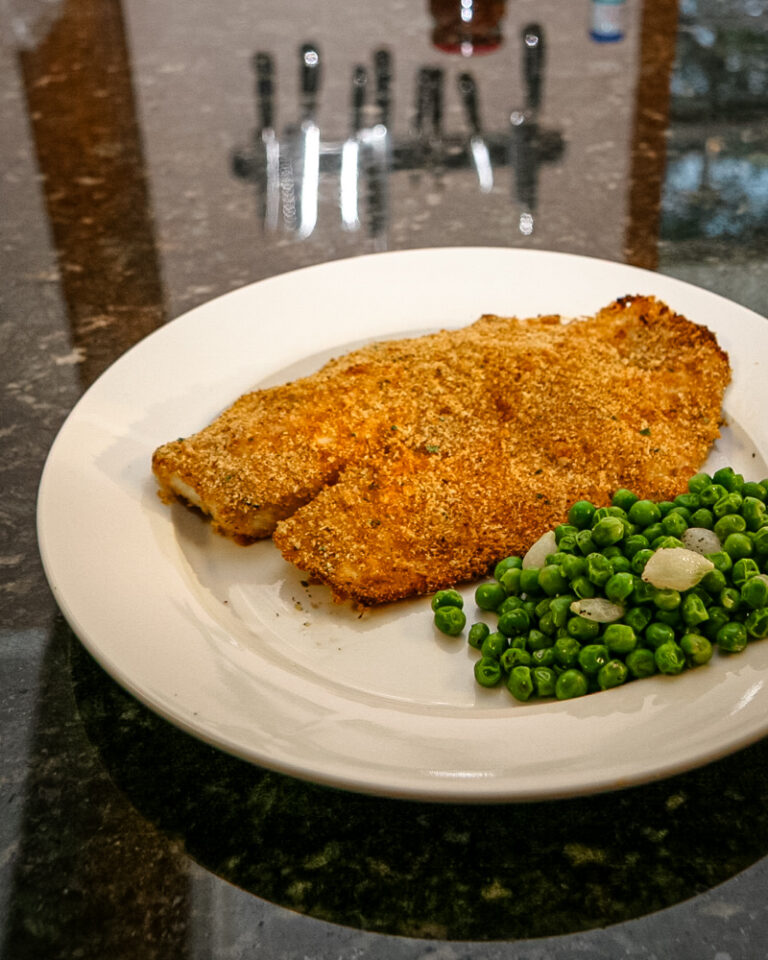 A plate with oven-fried tilapia and peas.