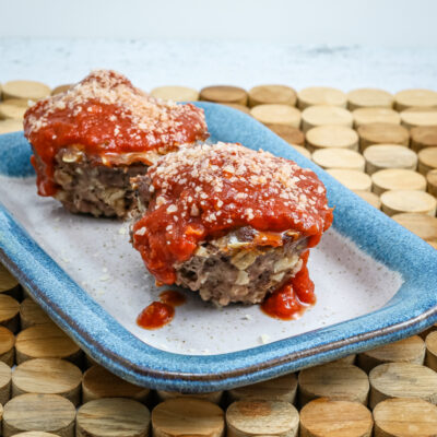 parmesan meatloaf in muffin shapes, topped with pizza sauce and extra parmesan cheese
