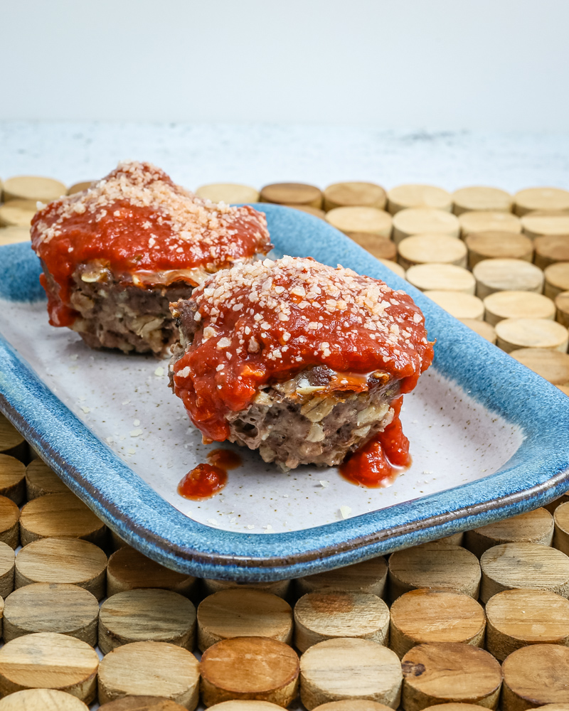 parmesan meatloaf in muffin shapes, topped with pizza sauce and extra parmesan cheese