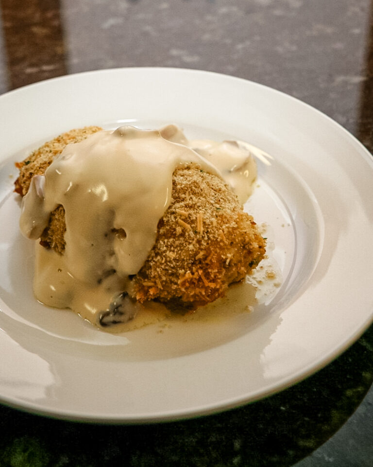 pesto chicken rolls on a plate with mornay sauce