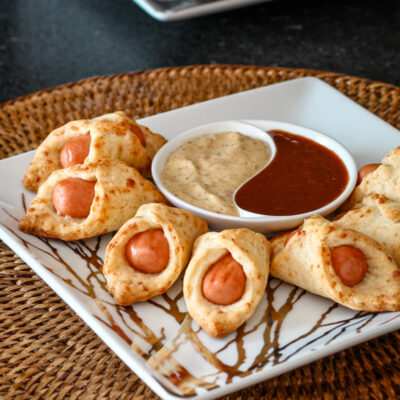 A small platter of pigs in a blanket with dips.