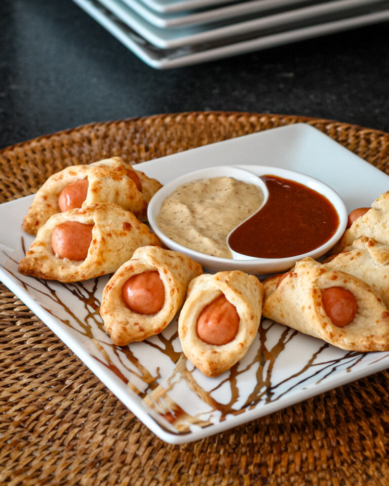 A small platter of pigs in a blanket with dips.