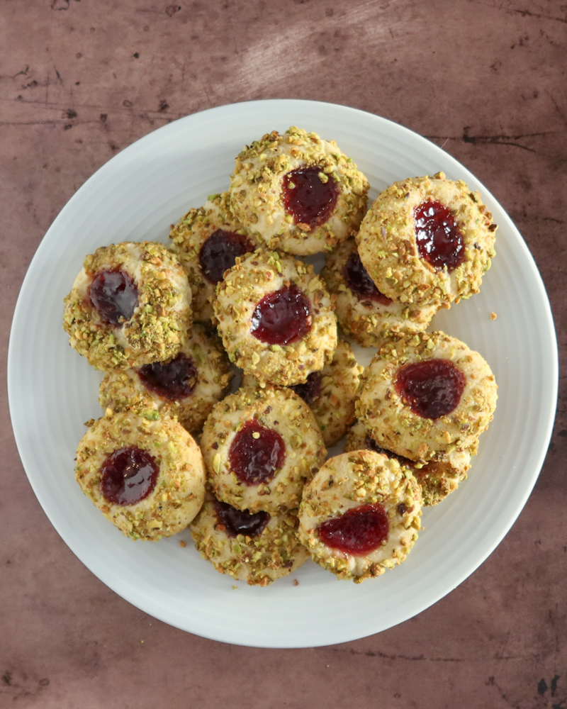 pistachio thumbprint cookies with jam center, arranged on a plate