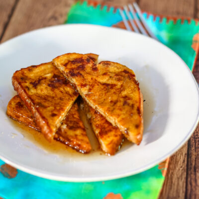 Pumpkin French toast sliced, on a plate with syrup and a fork.