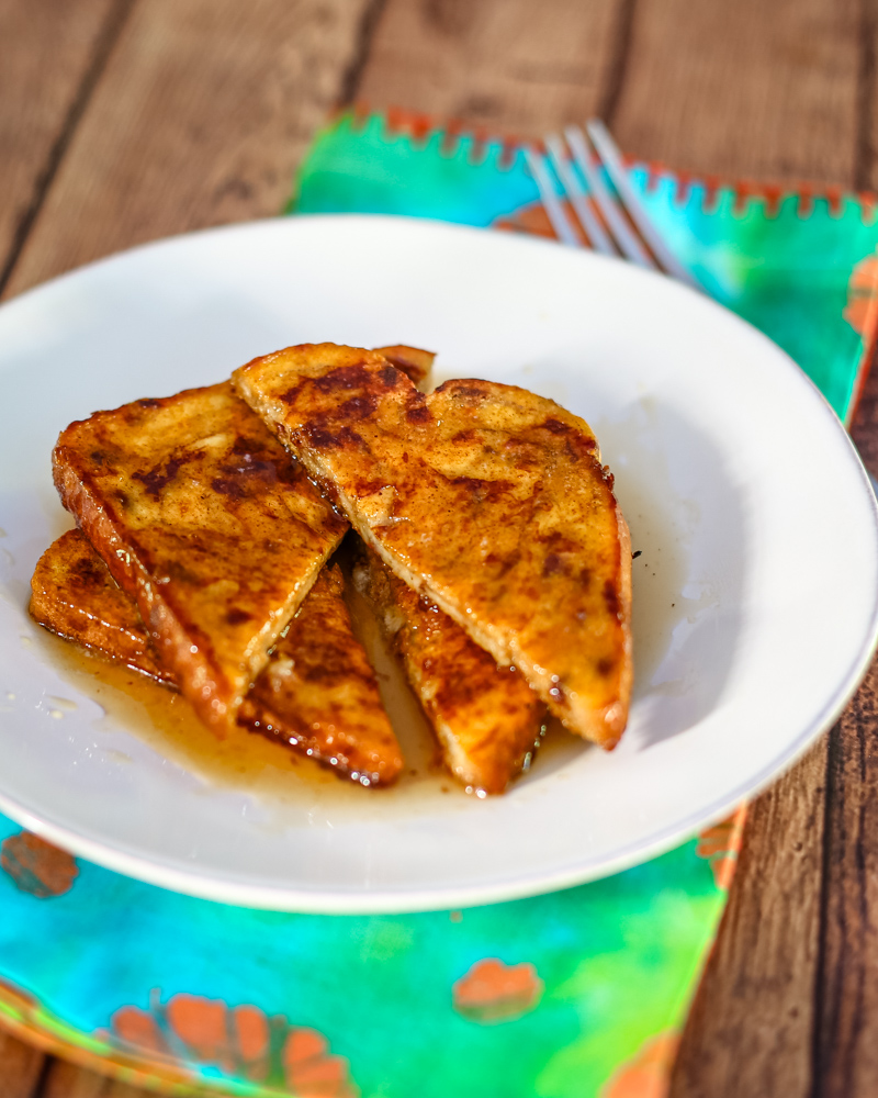 Pumpkin French toast sliced, on a plate with syrup and a fork.