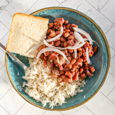 Black-eyed peas with rice and cornbread in a blue bowl with fork.