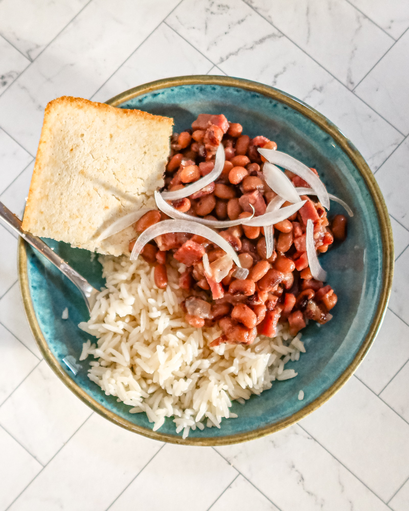Black-eyed peas with rice and cornbread in a blue bowl with fork.
