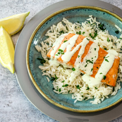 a salmon fillet on a bed of rice with a drizzle of basil mayonnaise.