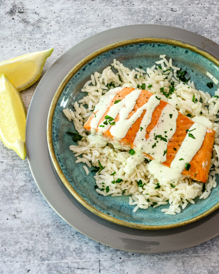 a salmon fillet on a bed of rice with a drizzle of basil mayonnaise.