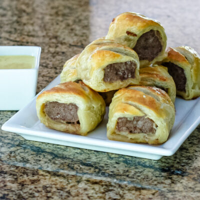 sausage rolls encased in puff pastry on a serving plate