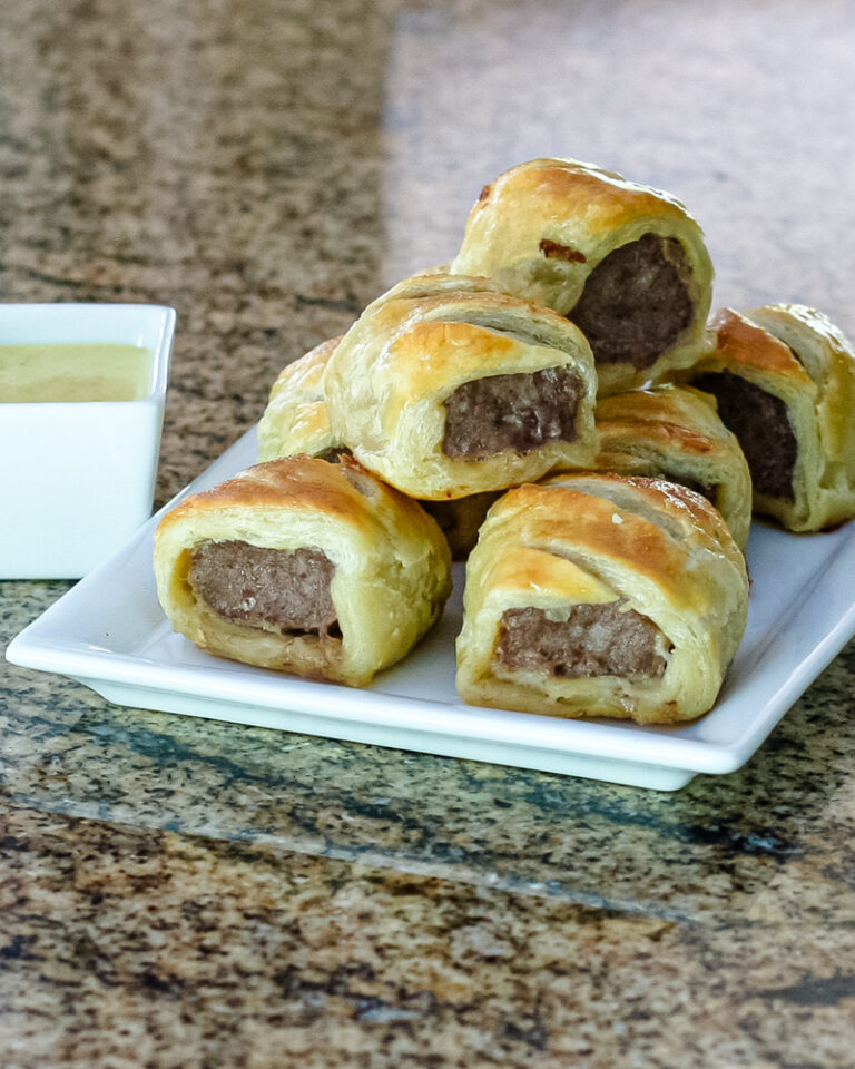sausage rolls encased in puff pastry on a serving plate