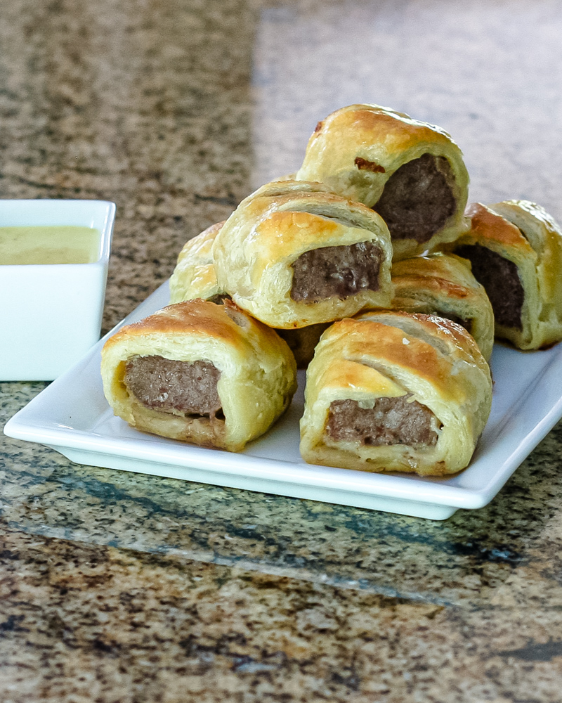sausage rolls encased in puff pastry on a serving plate