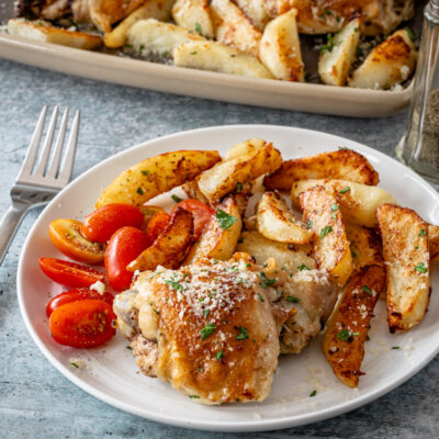 A serving of sheet pan garlic and parmesan chicken thighs with potatoes