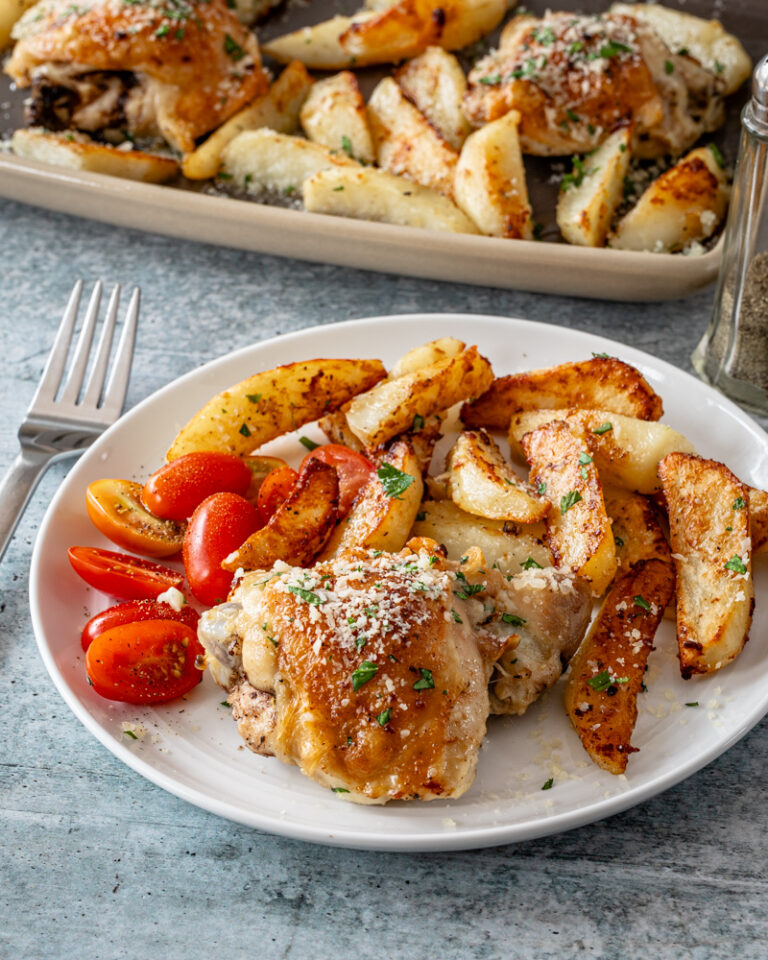 A serving of sheet pan garlic and parmesan chicken thighs with potatoes