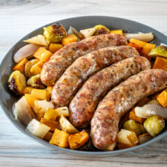 Sheet pan sausages surrounded by vegetables.