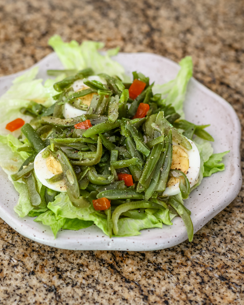 a simple green bean salad on a lettuce-lined plate