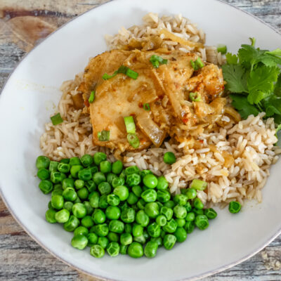 slow cooker chicken with curry flavor on a plate with rice and peas