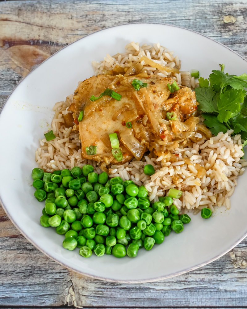 slow cooker chicken with curry flavor on a plate with rice and peas