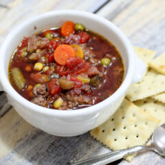 slow cooker hamburger soup in a bowl with crackers on the side.