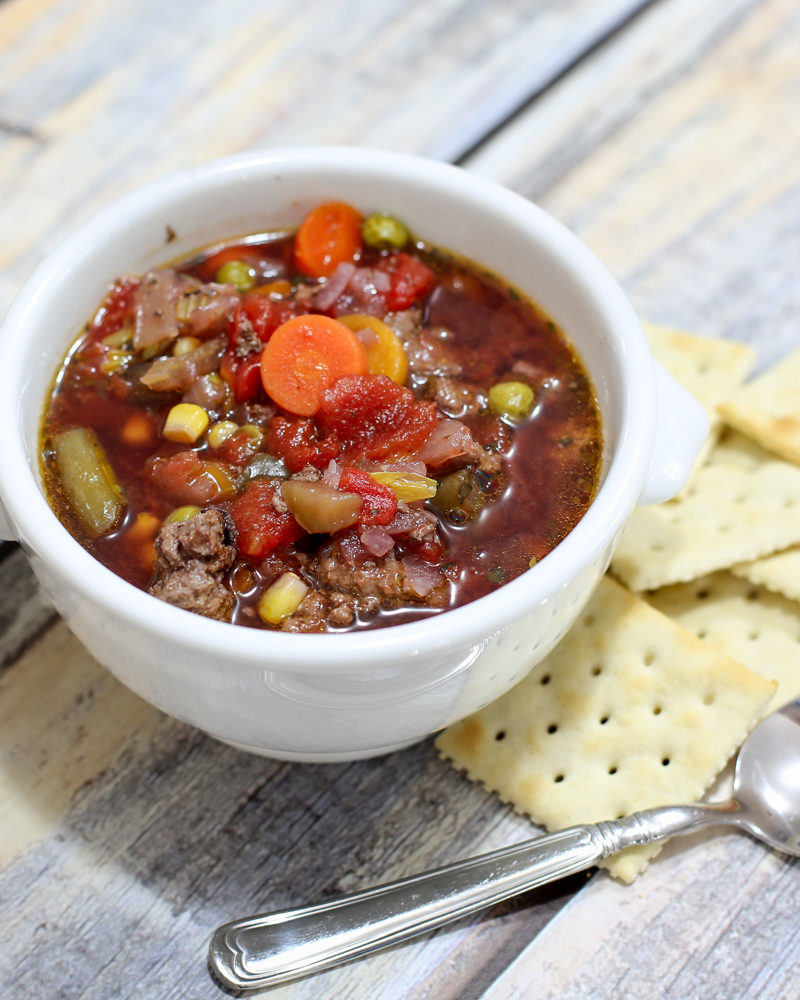 slow cooker hamburger soup in a bowl with crackers on the side.