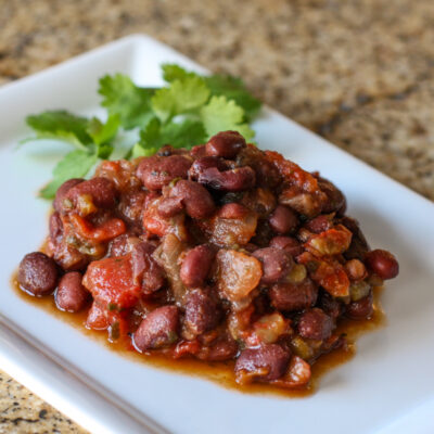 Tex Mex black beans and tomatoes on a plate with cilantro leaves.