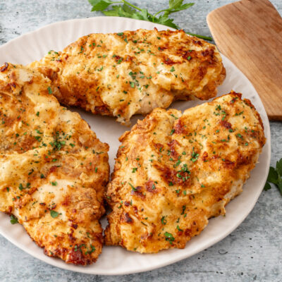Fried chicken breasts on a plate with parsley.