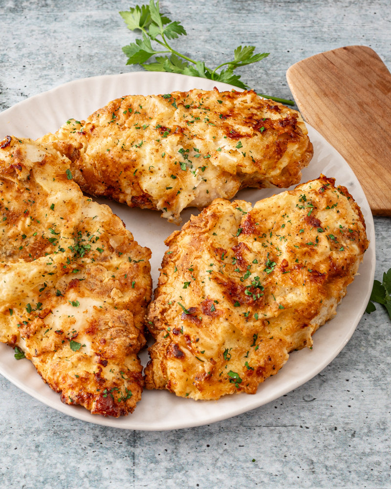 Fried chicken breasts on a plate with parsley.