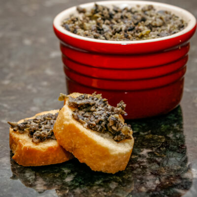 Olive tapenade spread on small crostini.