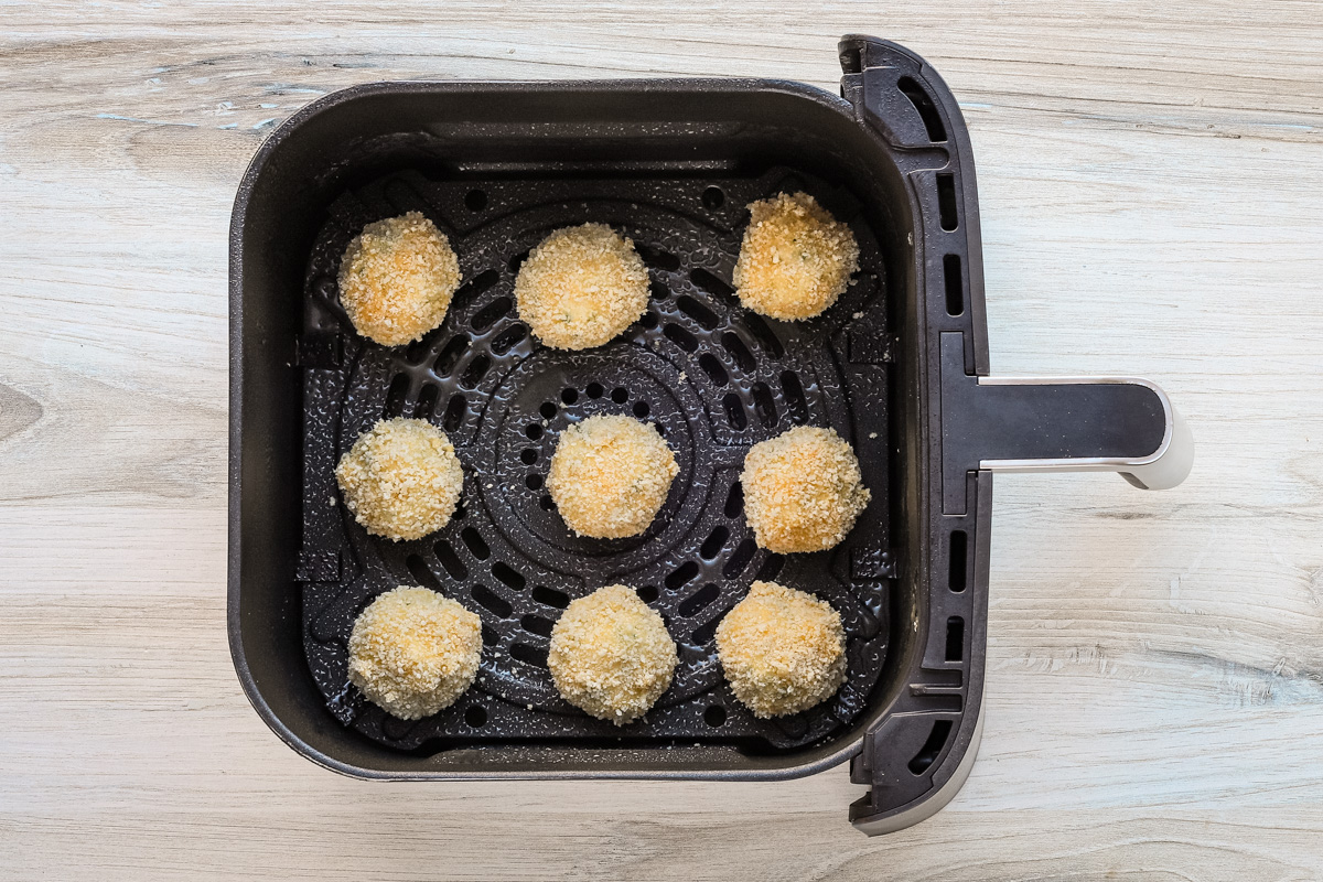 The potato croquettes are arranged in the air fryer basket.