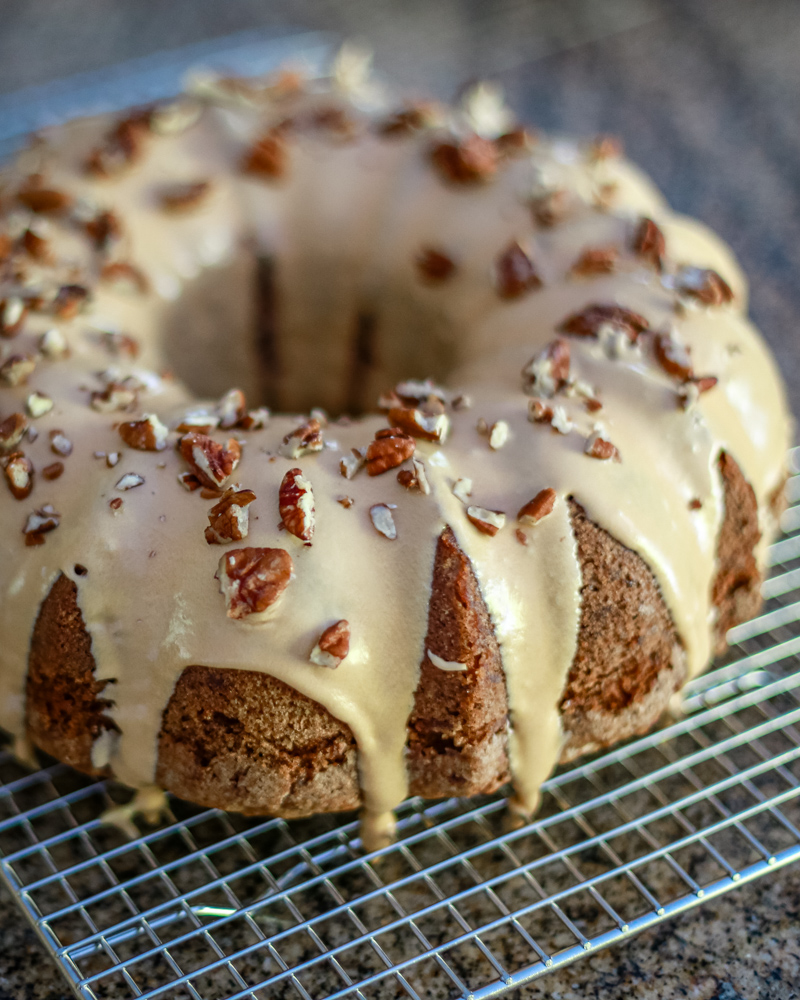 A glazed apple bundt cake on a cooling rack
