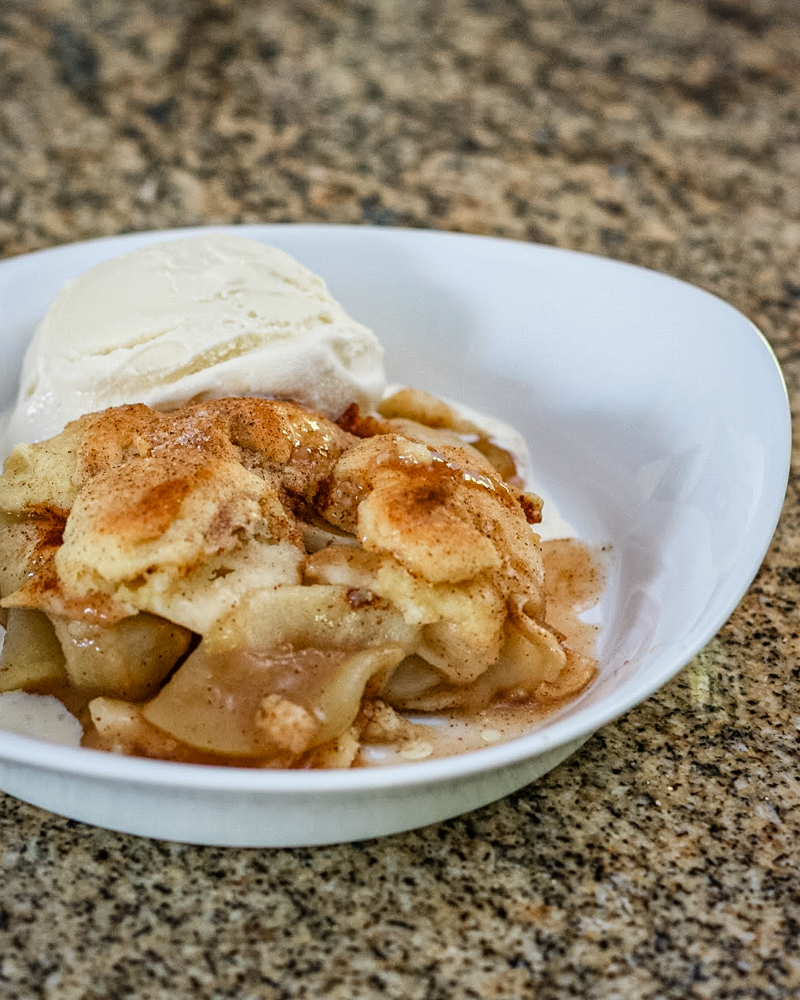 best ever apple cobbler in a serving dish with a scoop of ice cream