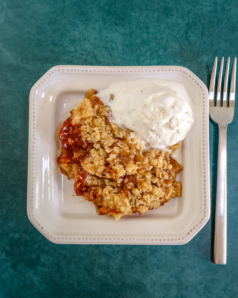 a serving of apple crisp on a plate with ice cream