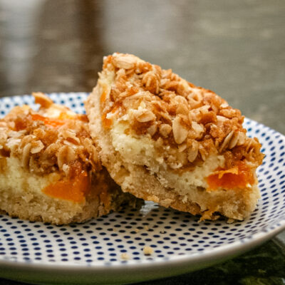 apricot cream cheese bars with shortbread crust and crumb topping, on a plate