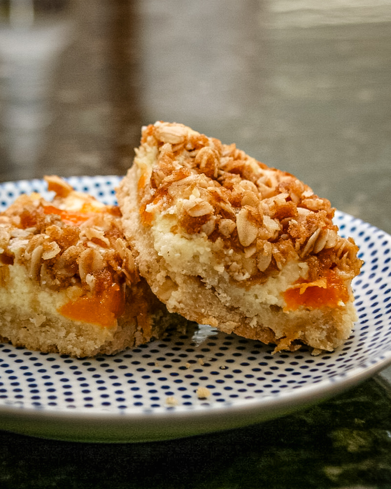 apricot cream cheese bars with shortbread crust and crumb topping, on a plate