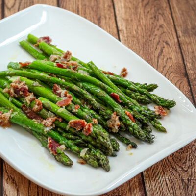 a plate of asparagus with bacon and light mustard sauce for flavor