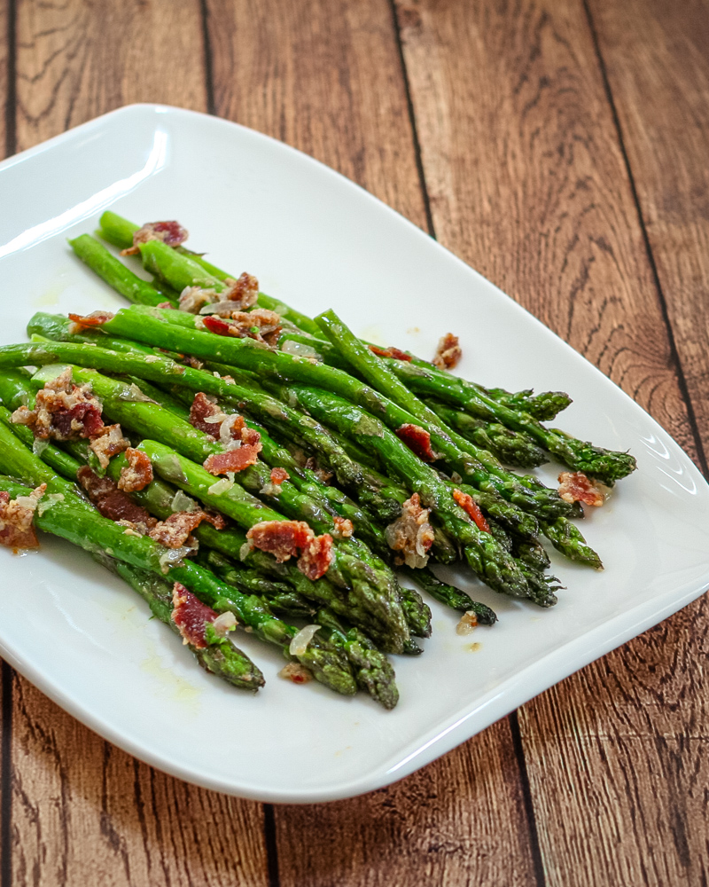 a plate of asparagus with bacon and light mustard sauce for flavor