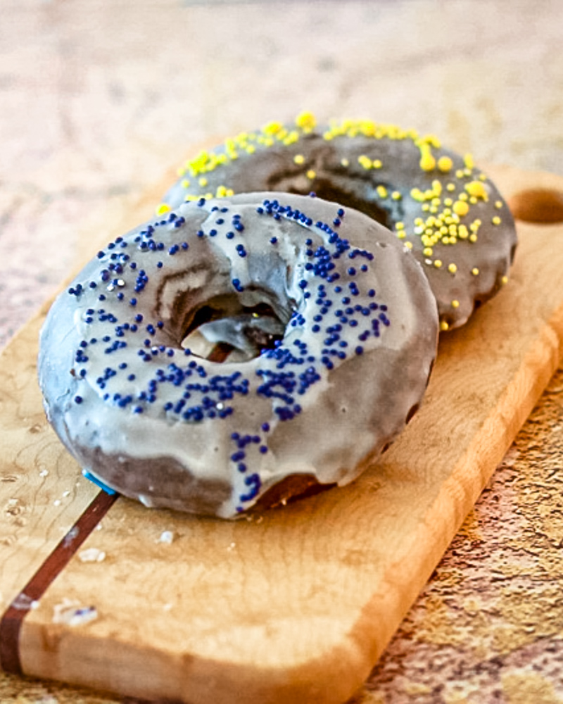 baked chocolate donuts with glaze and sprinkles on a small cutting board