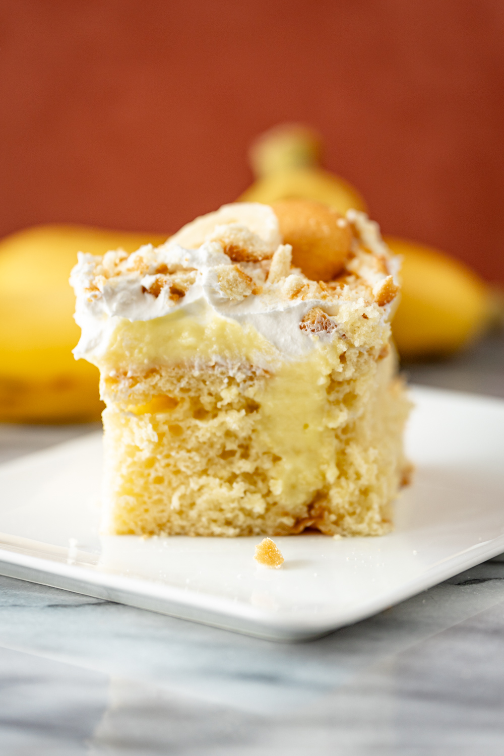 A banana pudding poke cake with whipped topping and vanilla wafers.