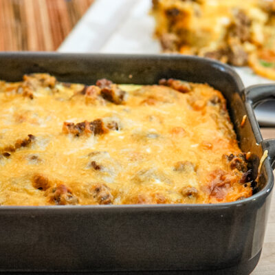 A breakfast casserole with cheese topping in a baking dish.