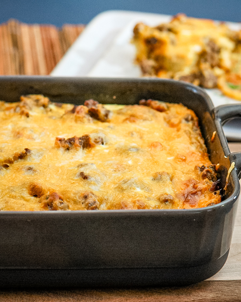 A breakfast casserole with cheese topping in a baking dish.