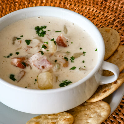 Clam chowder in a white bowl with crackers.