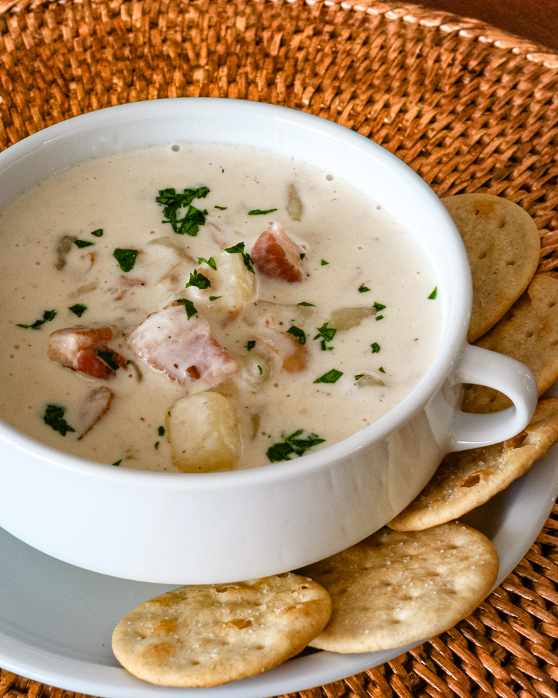 Clam chowder in a white bowl with crackers.