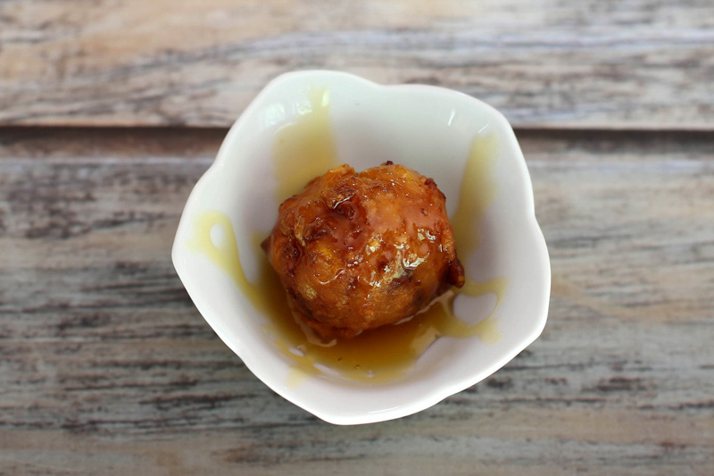 A corn fritter with a drizzle of golden syrup.