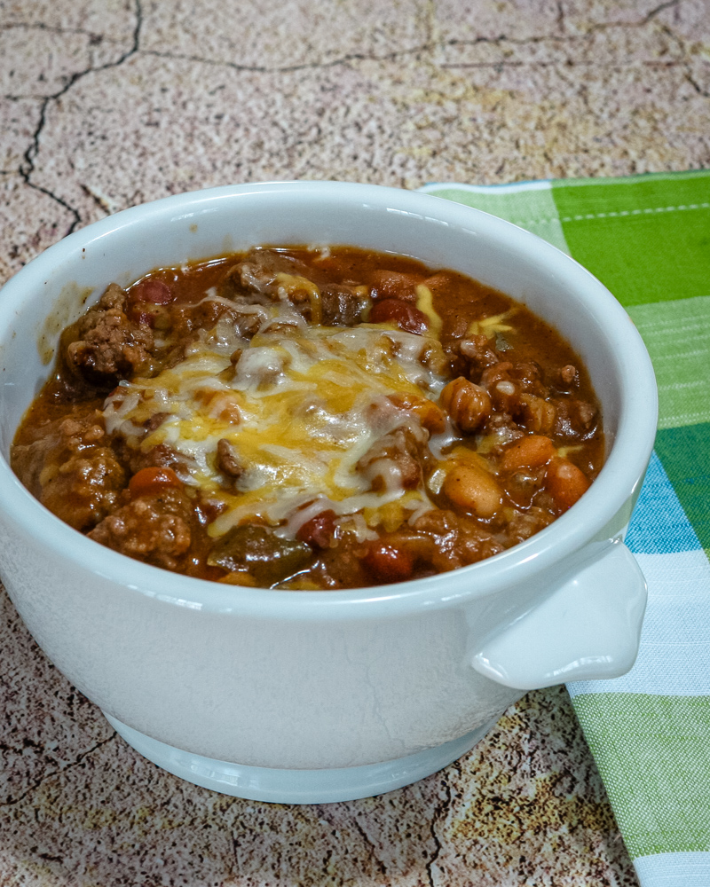 beef and beans with cheese in a bowl with napkin on the side