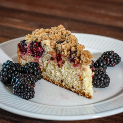 blackberry crumb cake on a plate with fresh blackberries