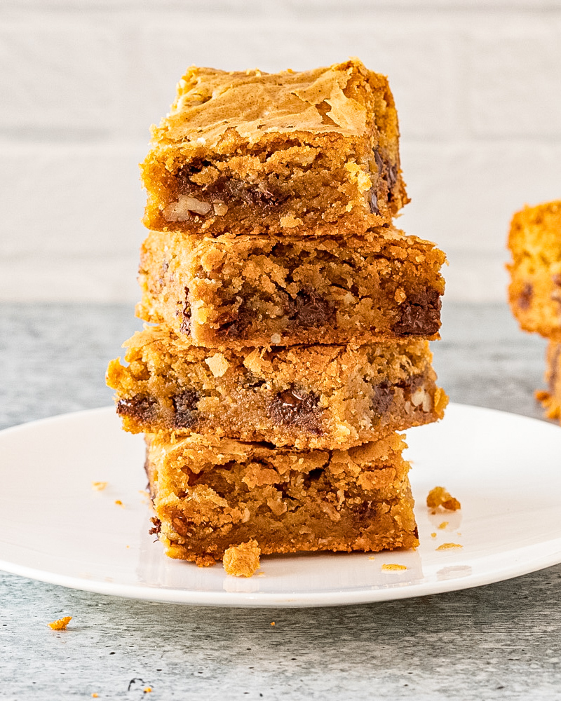 A stack of blondies on a dessert plate with a few more in the background.