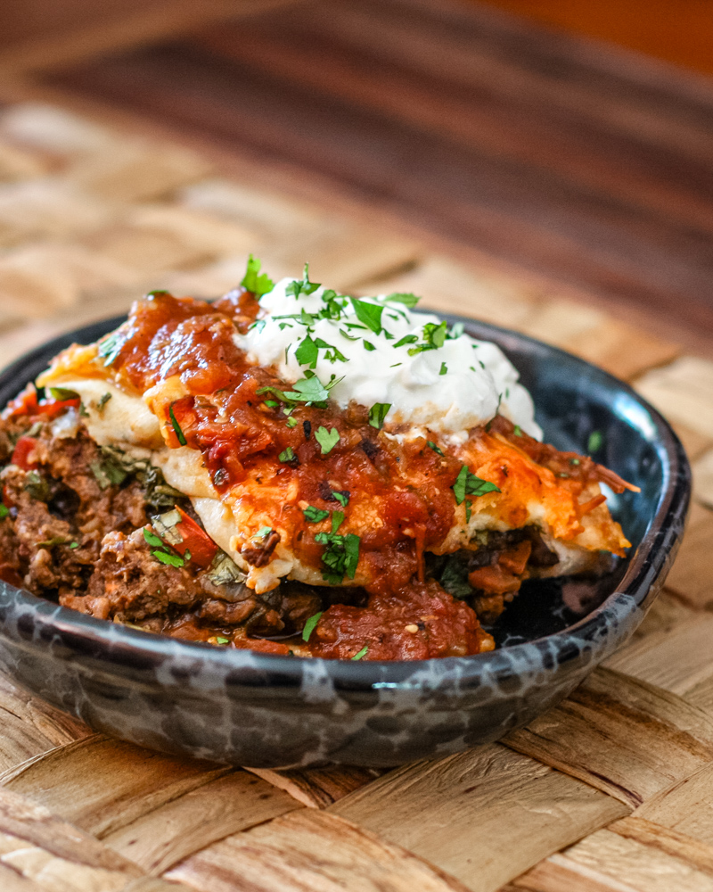 A burrito casserole serving with sour cream and cilantro topping.