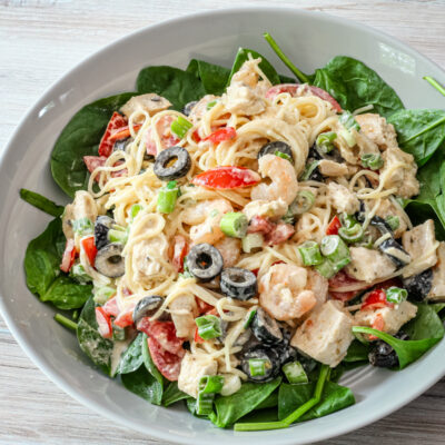 chicken and shrimp pasta salad with angel hair pasta and olives, in a serving dish