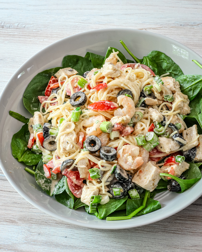 chicken and shrimp pasta salad with angel hair pasta and olives, in a serving dish