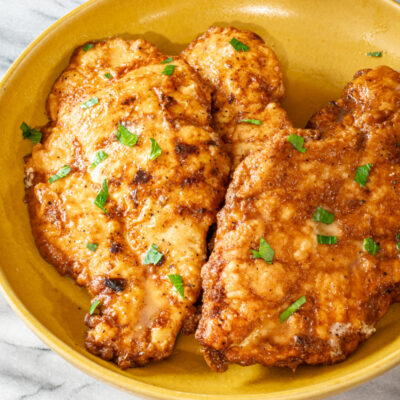 Chicken Francese in a bowl with parsley garnish.